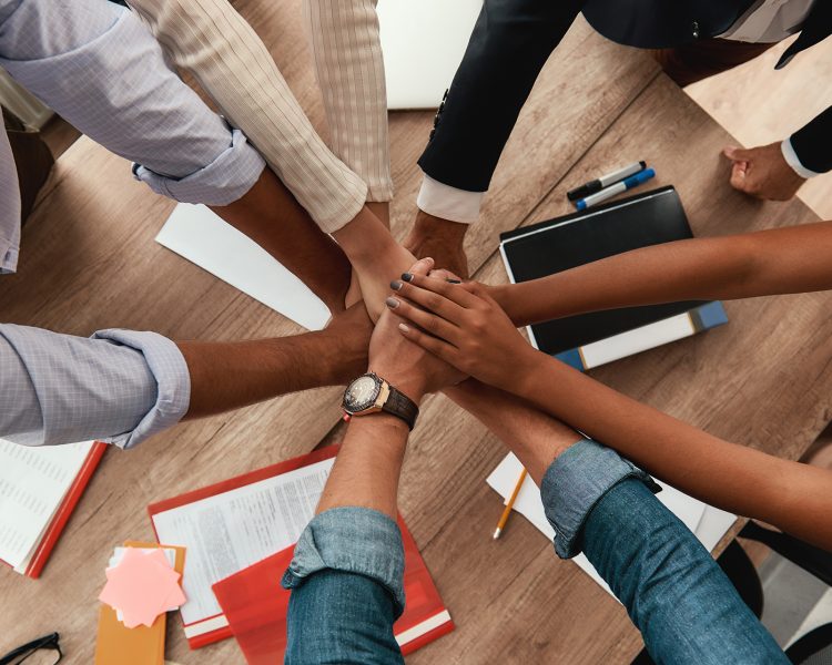 Multicultural team. Top view of business people holding hands together while sitting in the office. Teamwork. Success